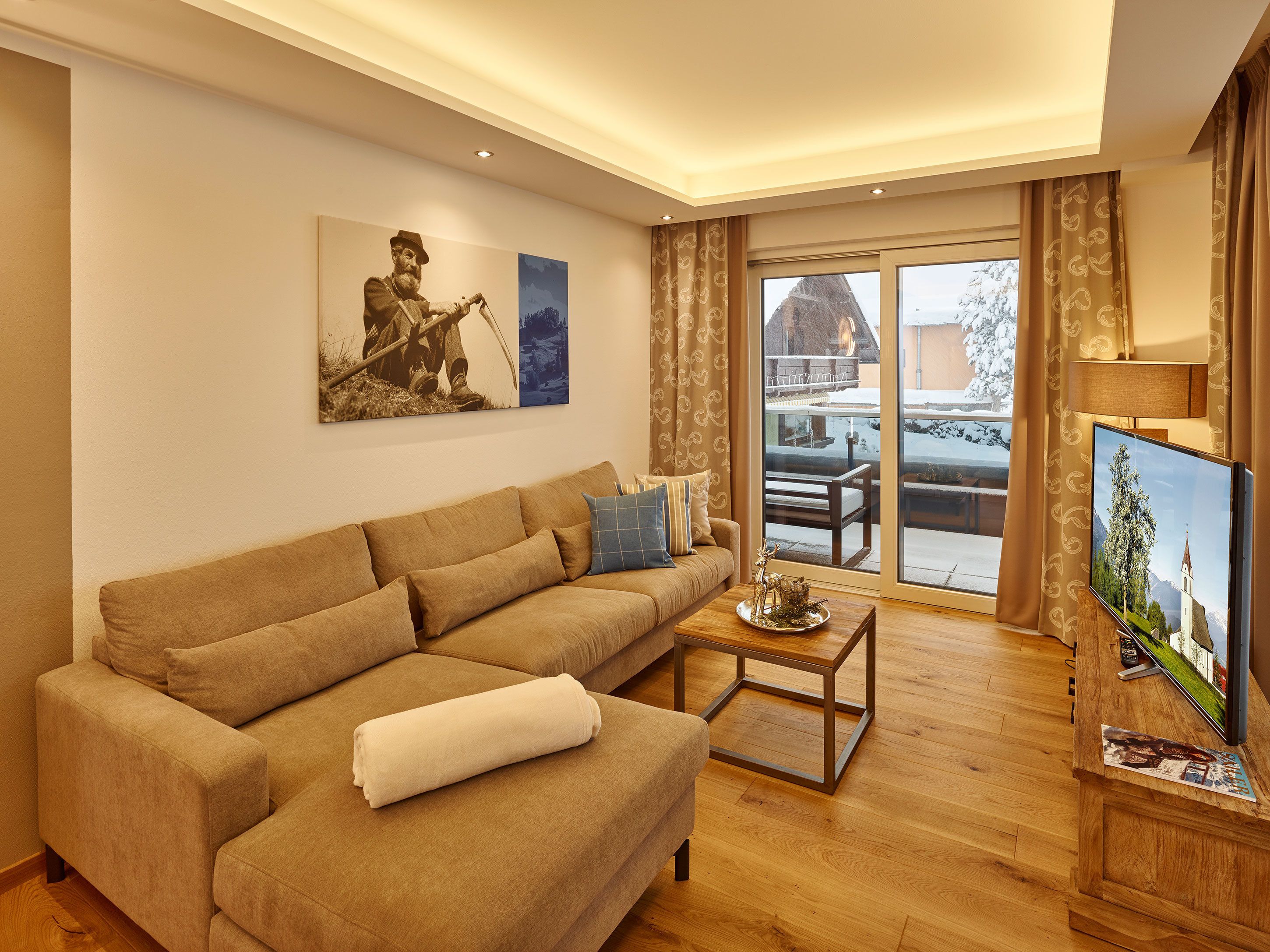 A living room with a sofa, a coffee table, a flat-screen TV, and a painting on the wall.