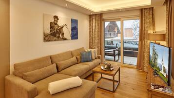 A living room with a sofa, a coffee table, a flat-screen TV, and a painting on the wall.