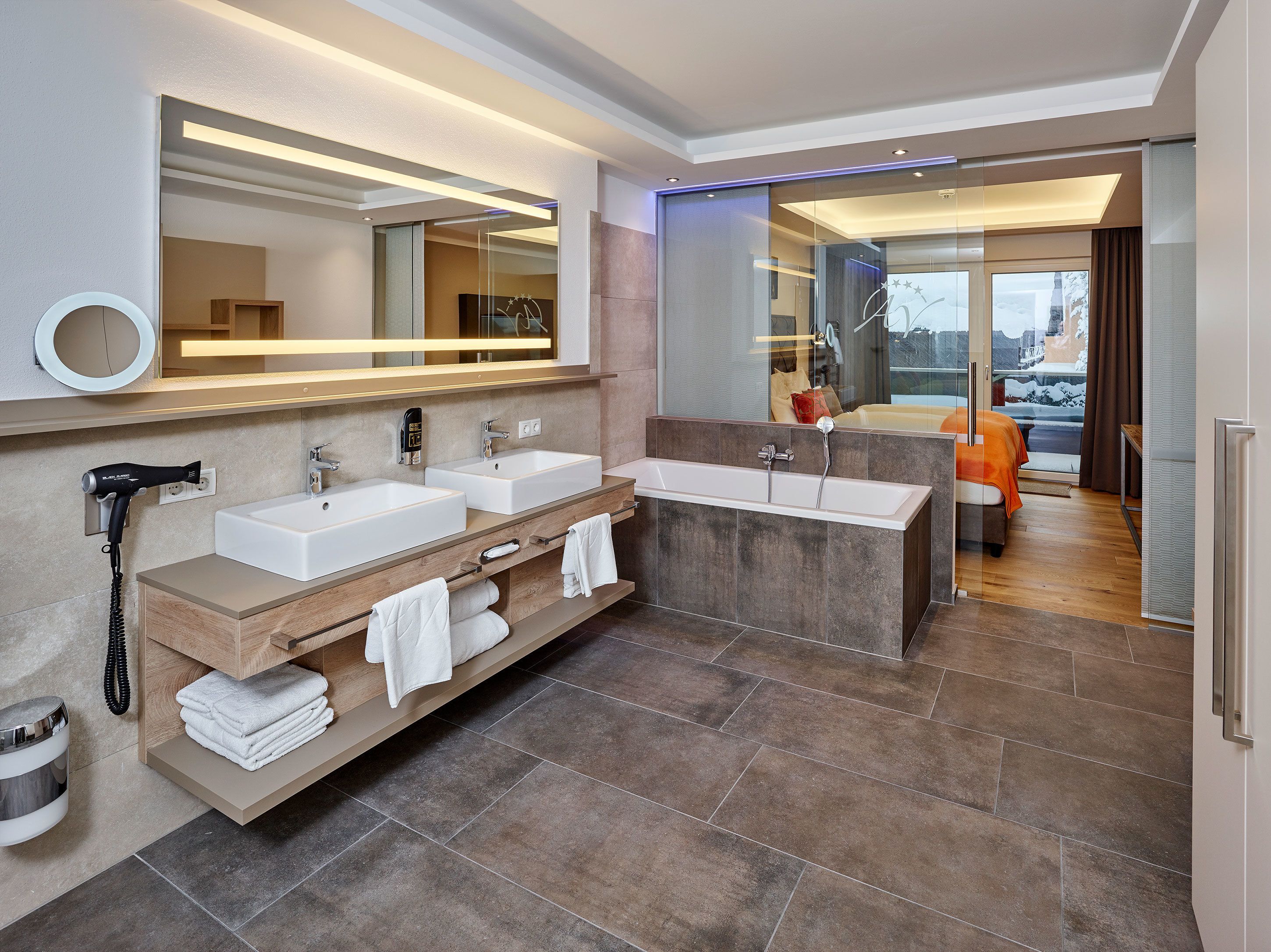 A modern bathroom with dual sinks, a large mirror, and a built-in shower.