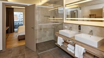 A modern bathroom with two sinks, a large mirror, and a shower area.