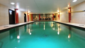 Una piscina con agua cristalina, rodeada de paredes de azulejos e iluminación empotrada en el techo.