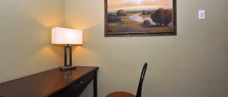 Una habitación con escritorio, silla y un cuadro en la pared.