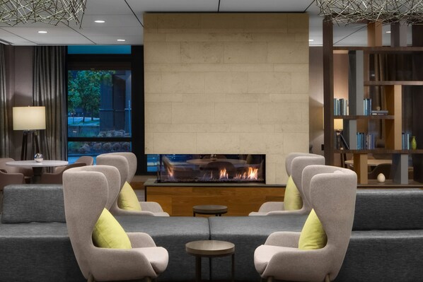 A modern lounge area with a fireplace, comfortable seating, and a bookshelf. - Courtyard by Marriott Seattle Bellevue/Downtown (Bellevue)