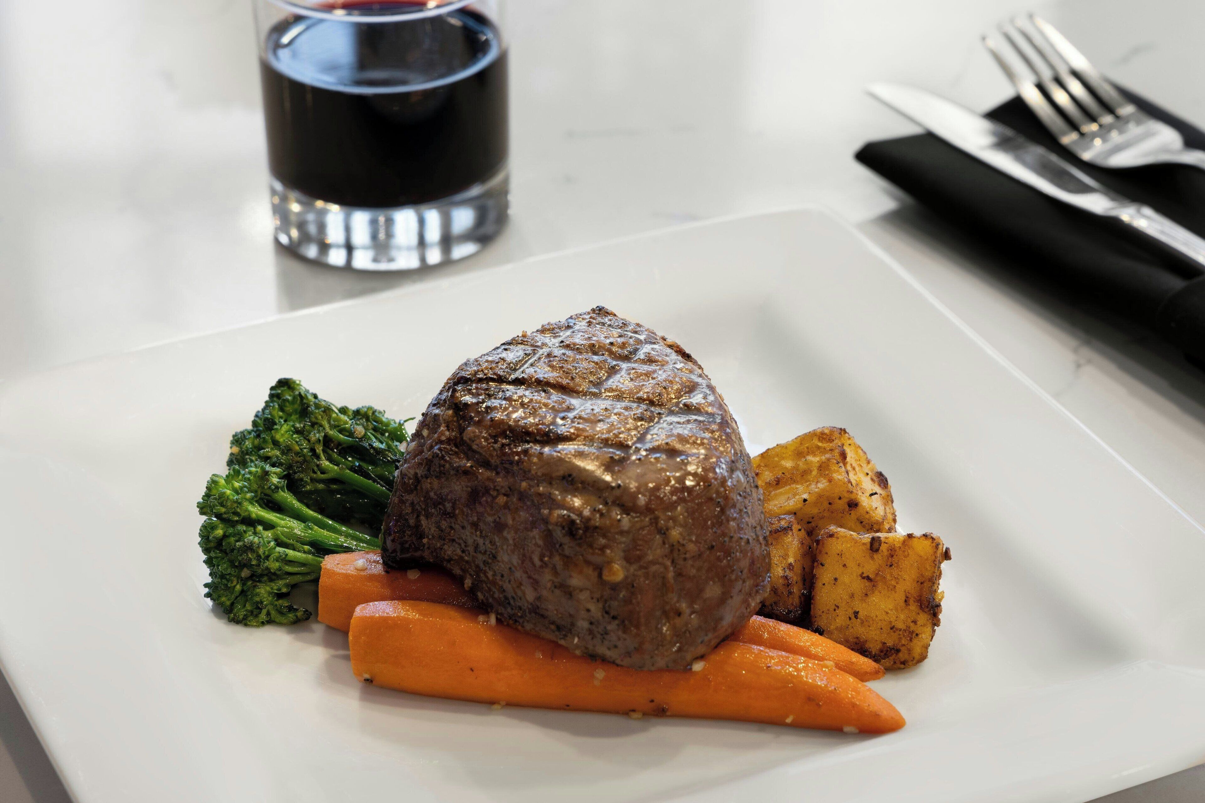 A plate with a steak, broccoli, and carrots.