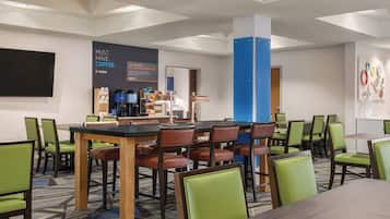 Habitación de hotel con comedor, zona de café y una gran pared con publicidad de café.
