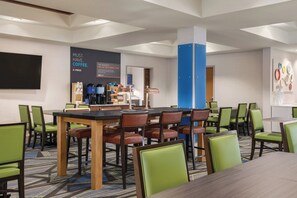 A hotel room with a dining area, a coffee station, and a large wall with a coffee advertisement.