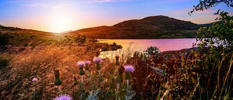 A sunset over a lake with hills in the background.