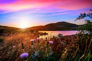 Ein Sonnenuntergang über einem See mit Hügeln im Hintergrund.