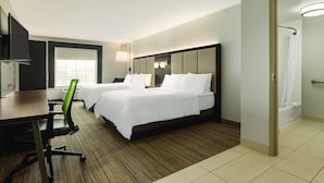 Ein Hotelzimmer mit zwei Betten, einem Schreibtisch, einem Stuhl, einer Dusche und einem Fenster.