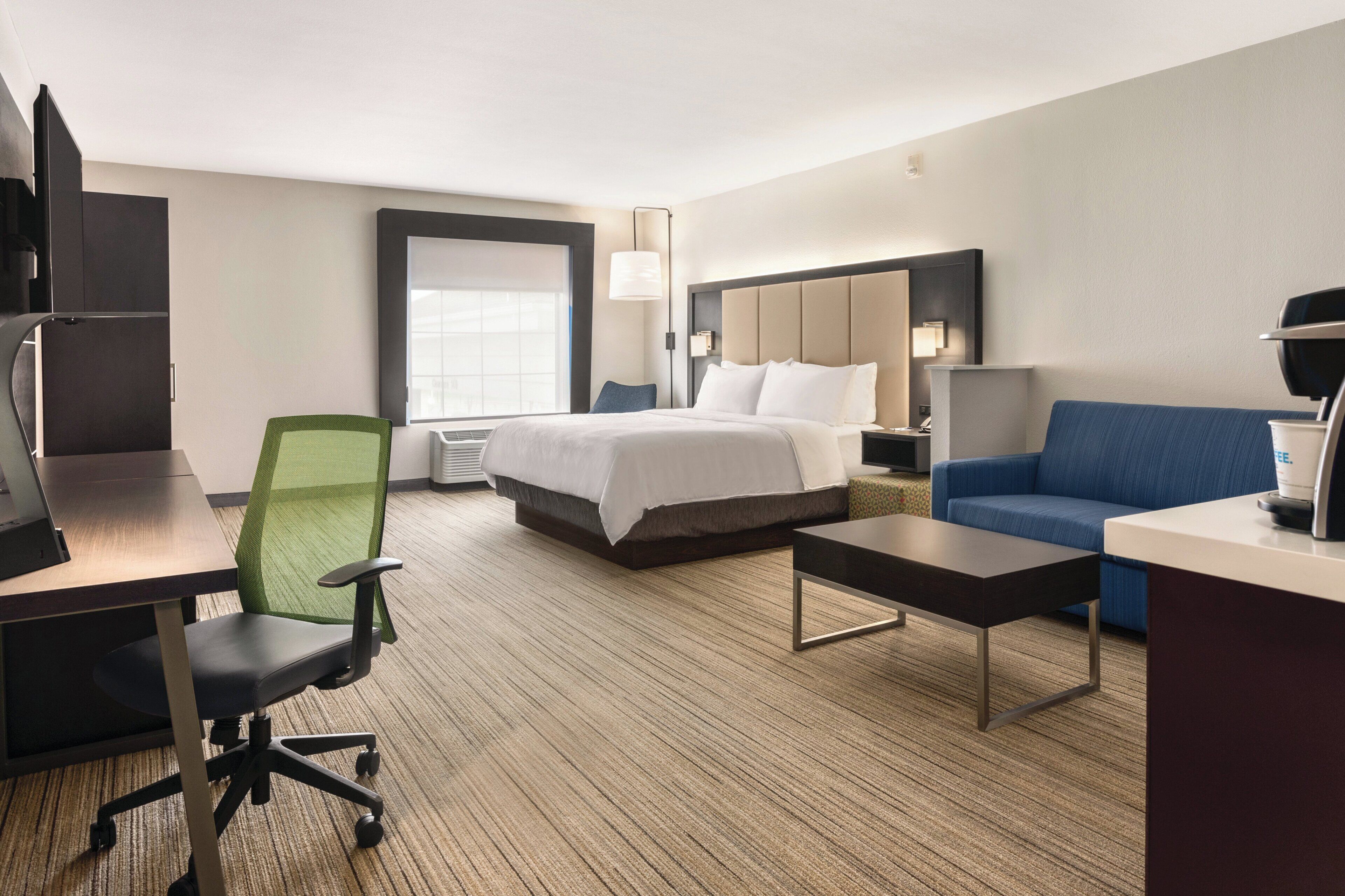 Une chambre d’hôtel équipée d’un lit, d’un bureau, d’une chaise, d’un canapé et d’une télévision.