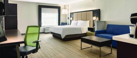 Una habitación de hotel con cama, escritorio, silla, sofá y televisión.