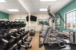 A gym with exercise equipment, including dumbbells, a stationary bike, and a rowing machine.