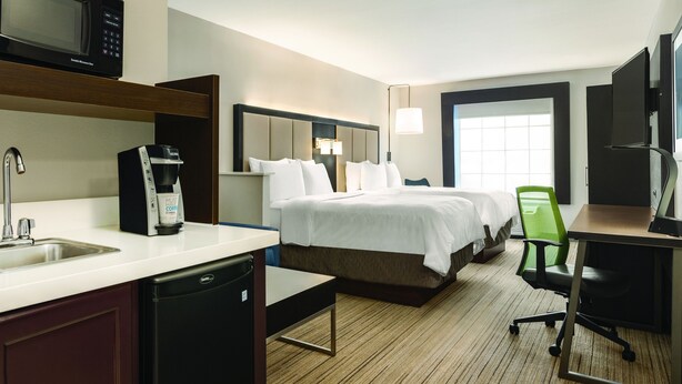 Ein Hotelzimmer mit Bett, Schreibtisch, Stuhl, Mikrowelle, Kaffeemaschine und Fernseher.