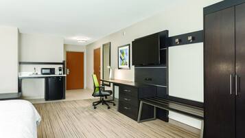 Een hotelkamer met een bed, een bureau met stoel, een televisie en een kledingkast.