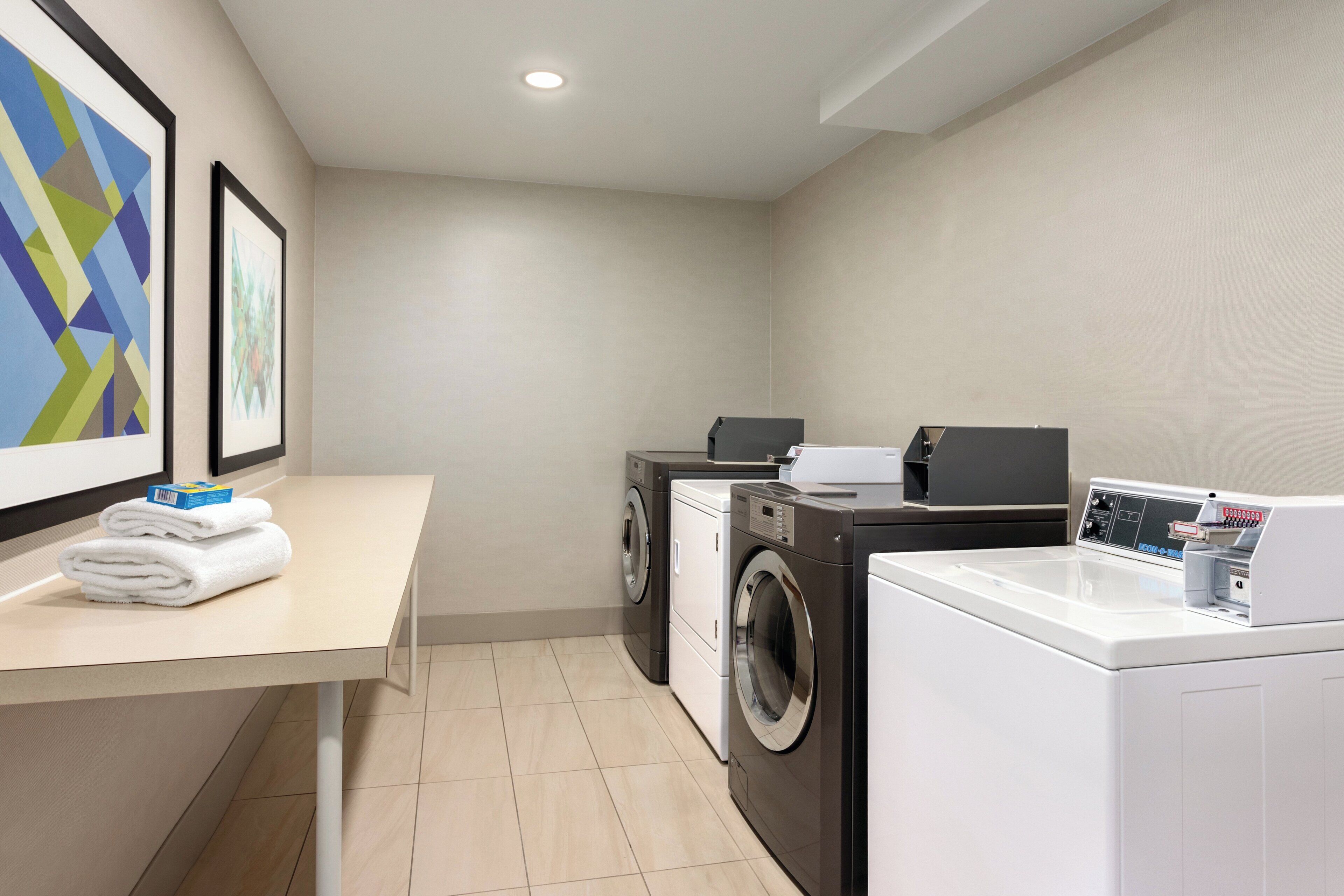 A laundry room with a washing machine, dryer, and a table with folded towels.