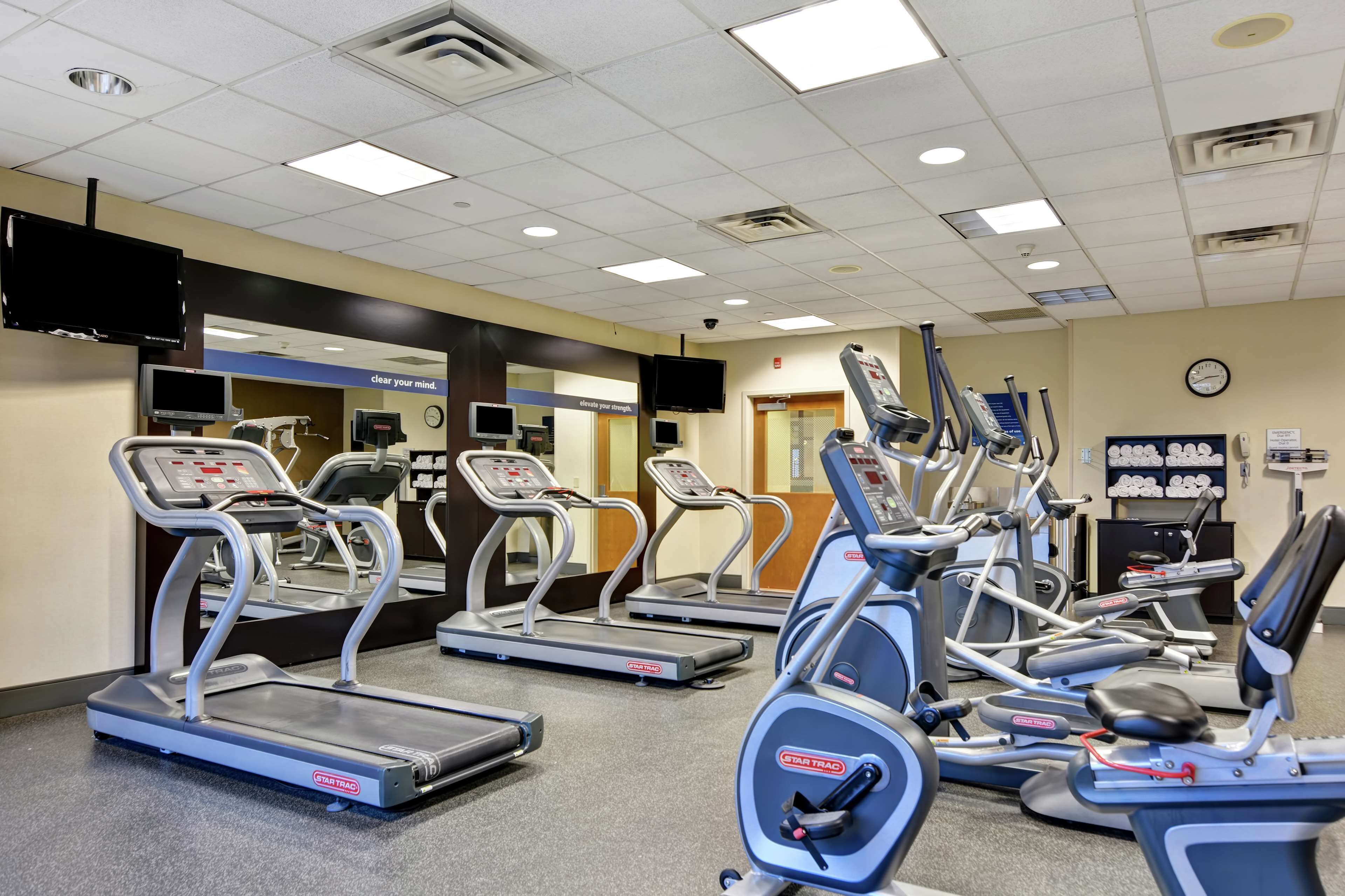 Un gimnasio con cintas de correr, elípticas y bicicletas estáticas.