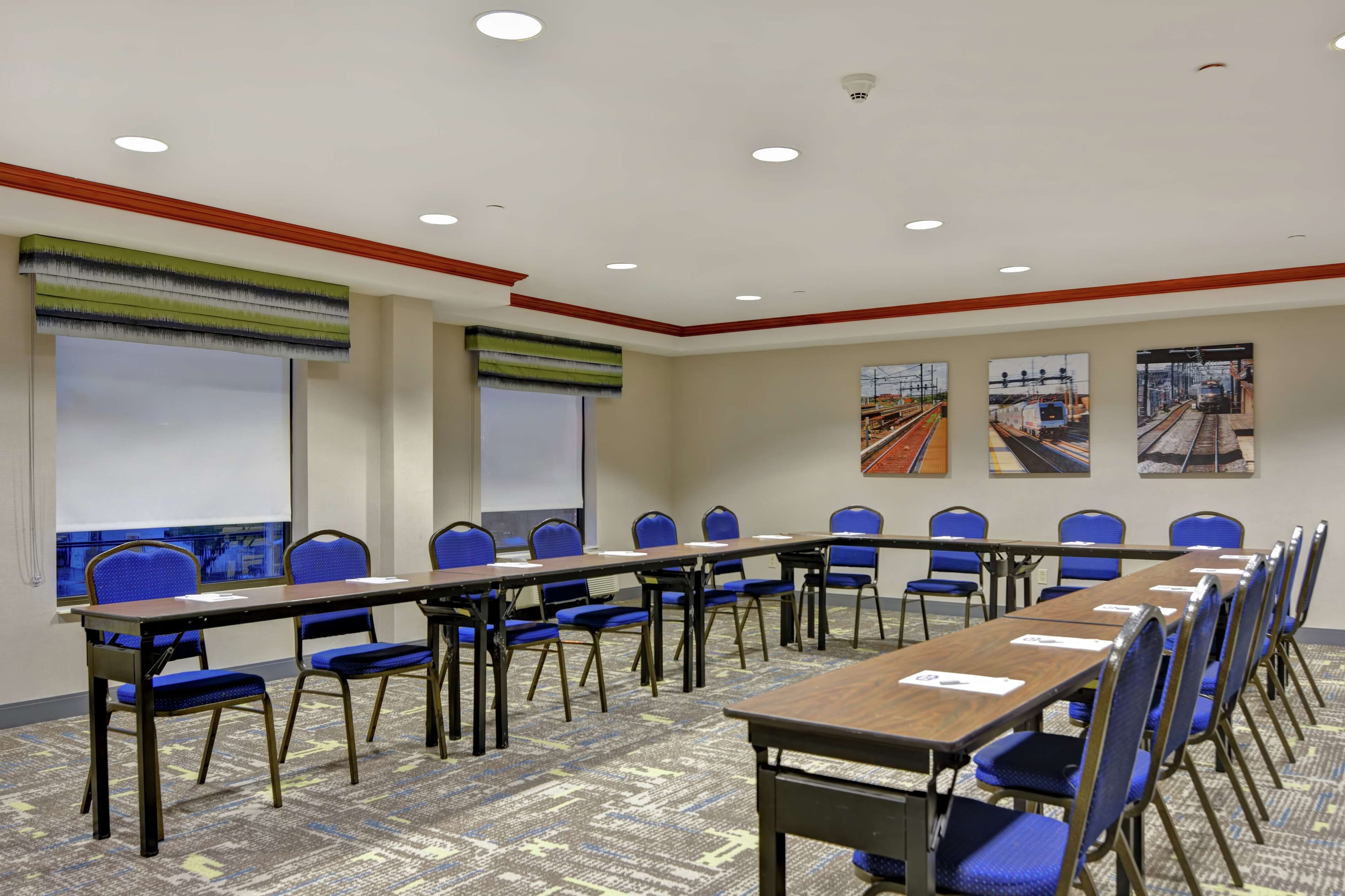 Un salón de conferencias con una larga mesa, sillas azules y piso alfombrado.
