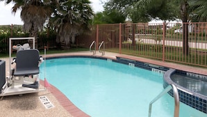 Una piscina con una silla de salvavidas y una cerca de metal.