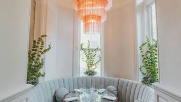 A dining area with a round table set for four, surrounded by a grey upholstered sofa with patterned cushions.