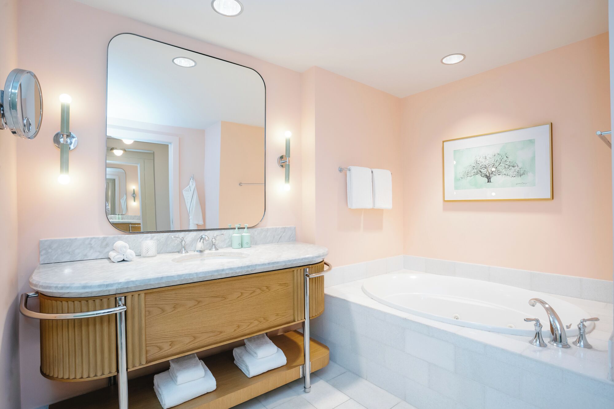 Un baño moderno con un espejo grande, una bañera y un tocador de madera con toallas.
