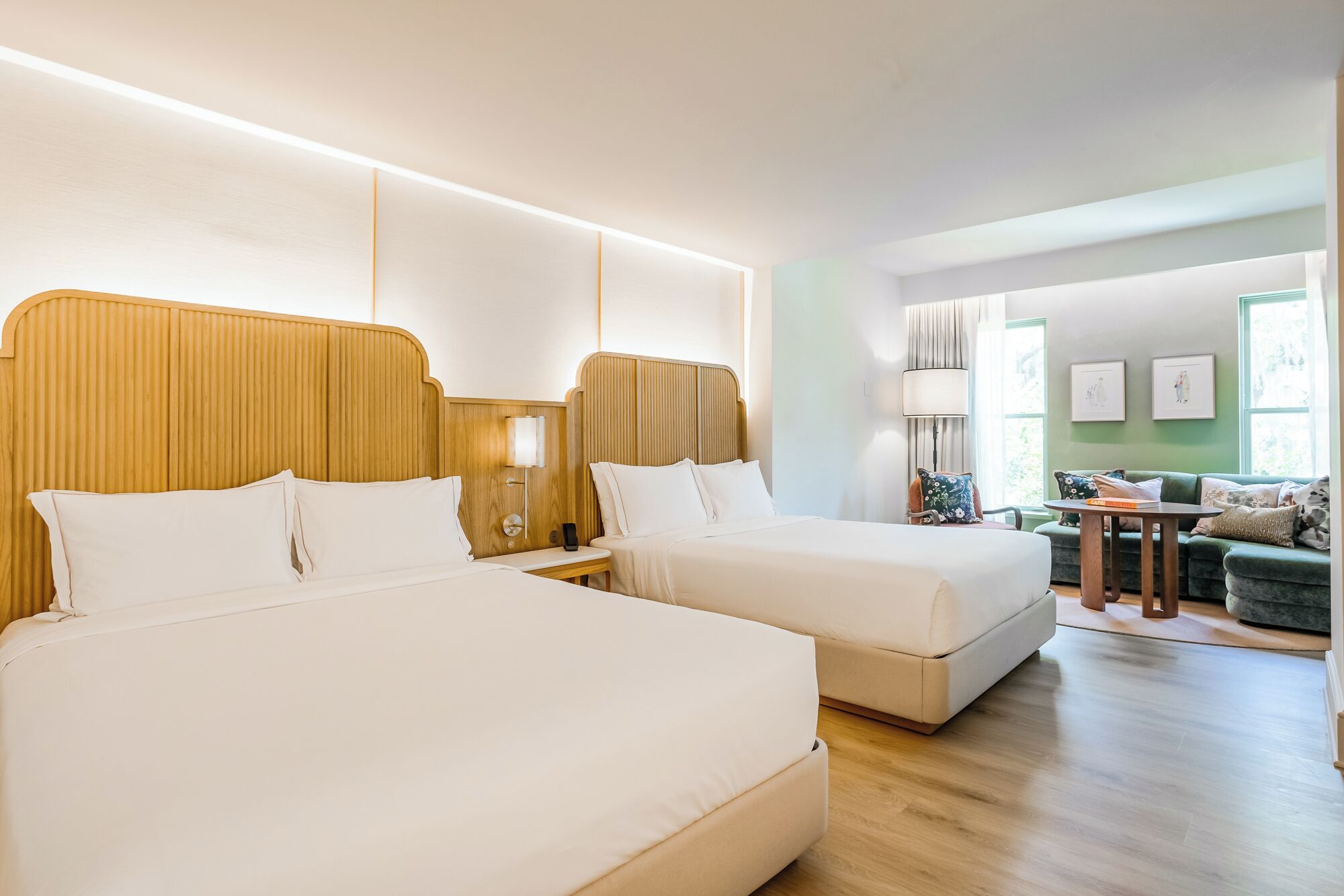 A hotel room with two beds, a sofa, and a small table.