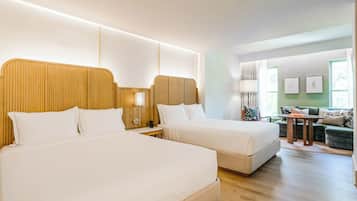 A hotel room with two beds, a sofa, and a small table.