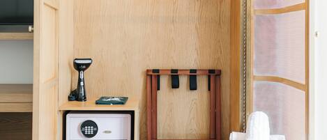 A wooden closet with a hanging rack, a safe, and a towel on a bench.