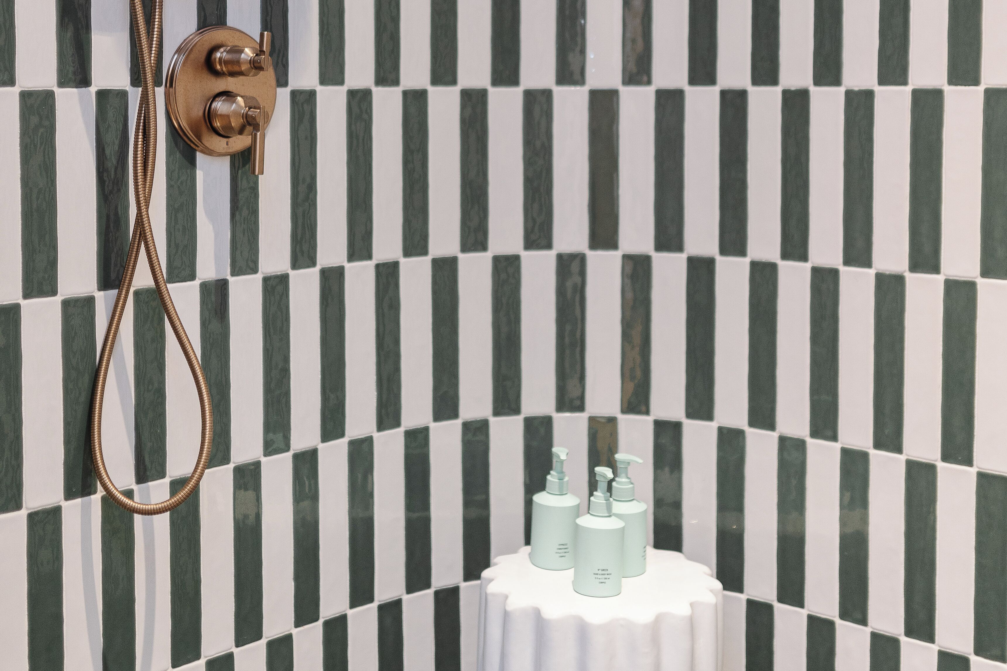A bathroom with a shower, a towel rack, and toiletries on a small table.
