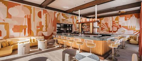 Un área de bar moderna con asientos, una barra y una pared decorativa.