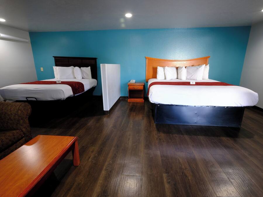 Une chambre d’hôtel avec deux lits, un canapé, une table en bois et une table de chevet.