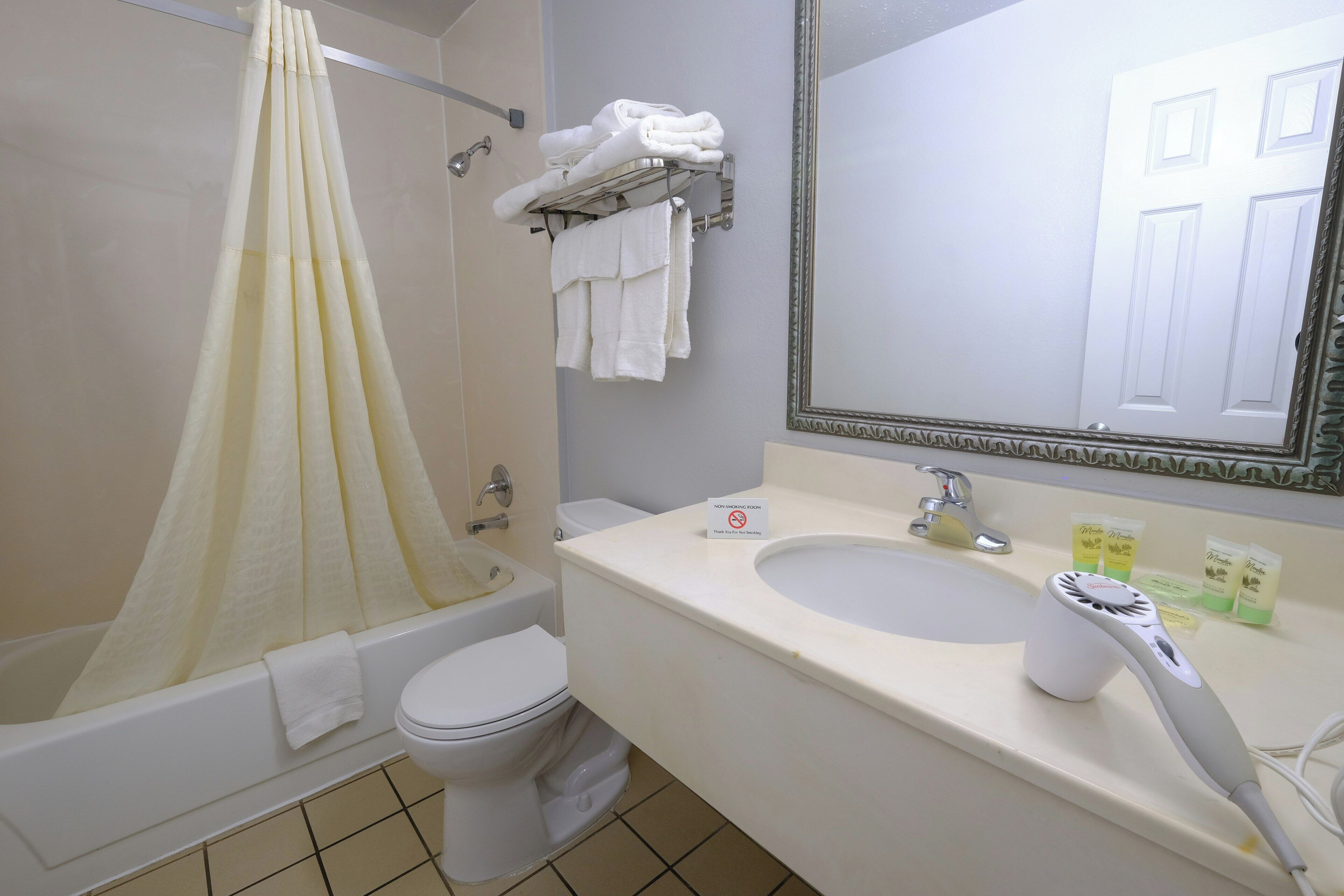 A bathroom with a bathtub, toilet, sink, and a towel rack with folded towels.