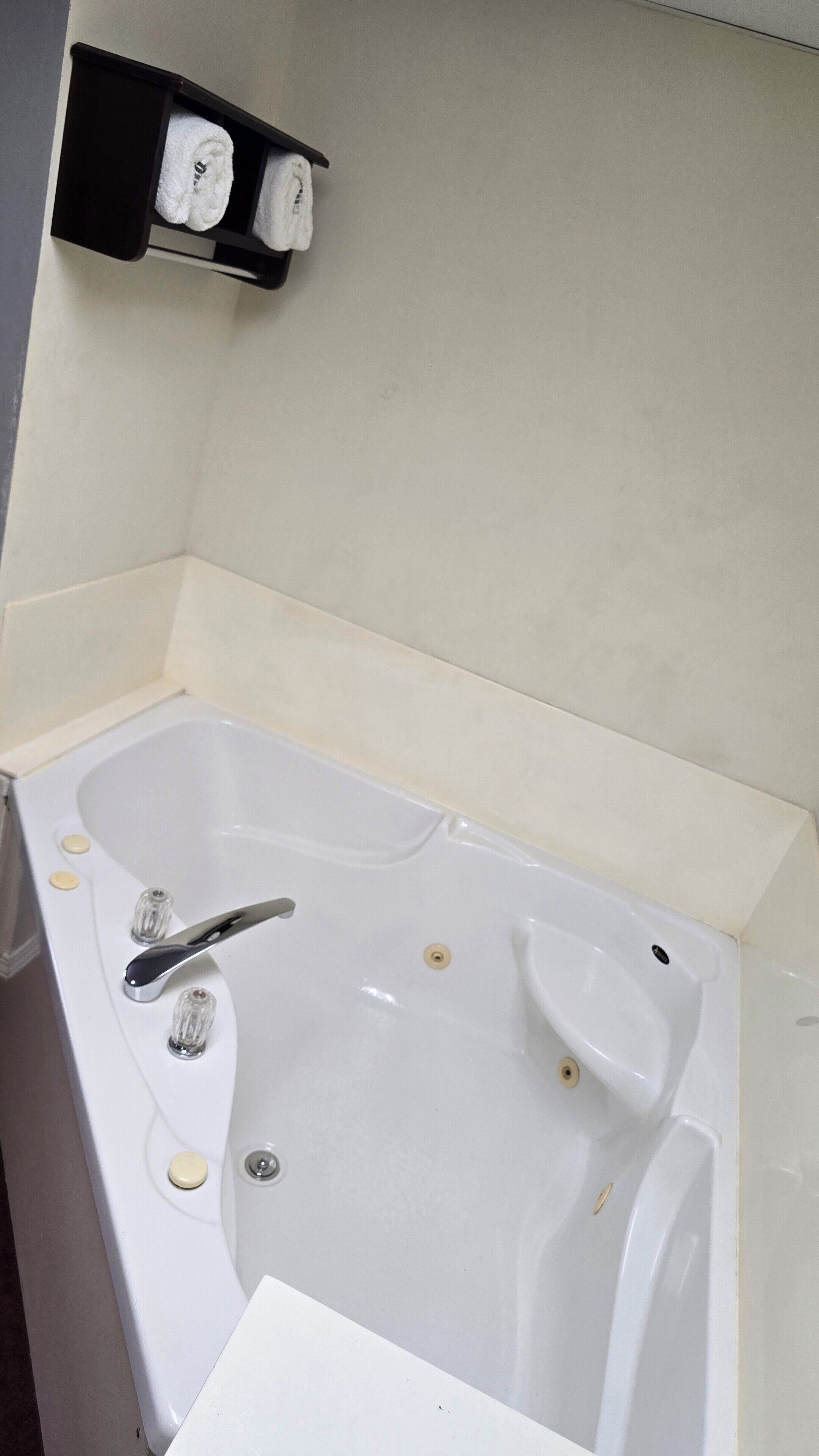 A white bathtub with a chrome faucet, a soap dish, and a towel rack with two towels.