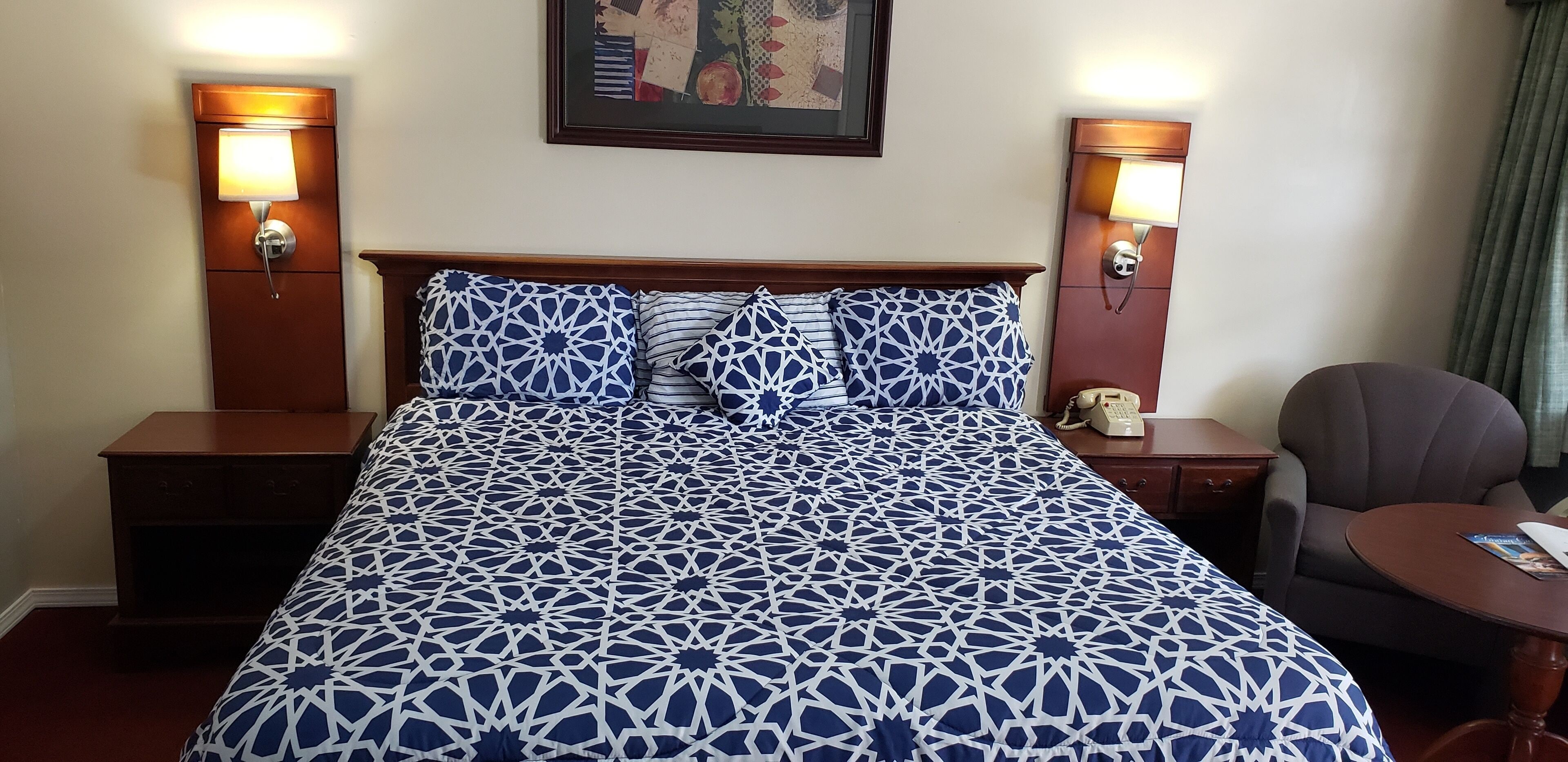 A hotel room with a large bed, two bedside tables, a chair, and a small table.
