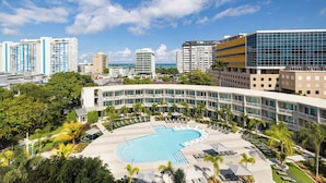 A hotel with a pool, surrounded by greenery and modern buildings. - Hyatt Centric San Juan - Isla Verde (Carolina)