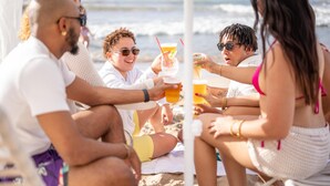A group of people sitting on a beach, holding drinks. - Hyatt Centric San Juan - Isla Verde (Carolina)