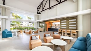 A spacious lobby with modern furniture, a bar area, and large windows offering a view of the outdoors. - Hyatt Centric San Juan - Isla Verde (Carolina)