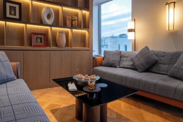A modern living room with a sofa, a coffee table, and a wall-mounted shelf with decorative items.
