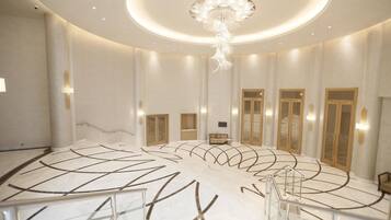 A spacious lobby with a central staircase, a chandelier, and a seating area.