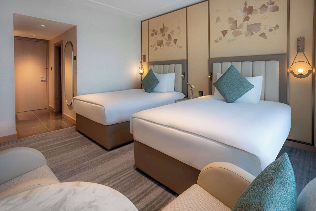 Ein Hotelzimmer mit zwei Betten, einem Sofa und Teppichboden.