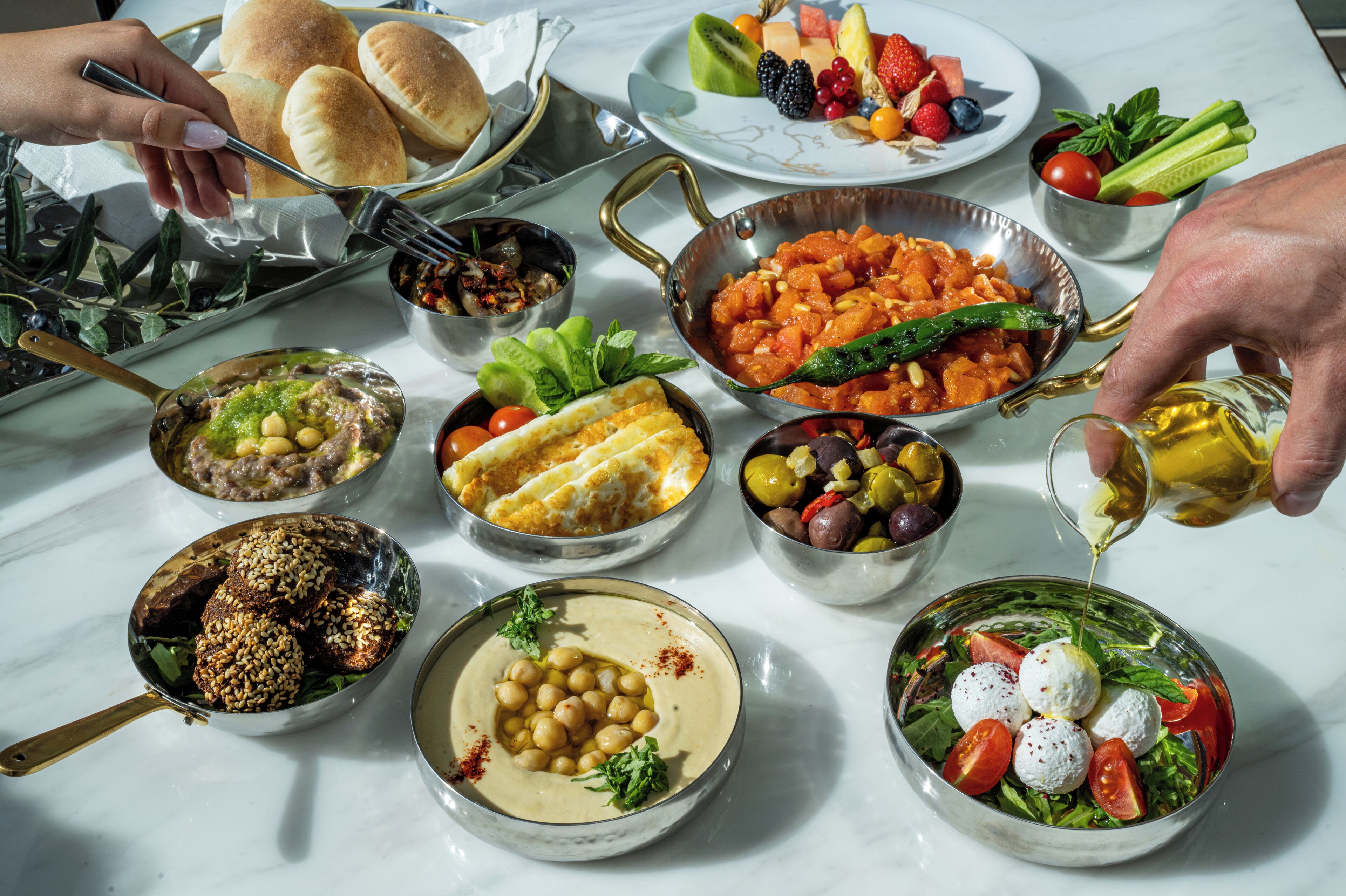 Una selezione di piatti, tra cui hummus, falafel e un'insalata con pomodori e bocconcini di mozzarella.