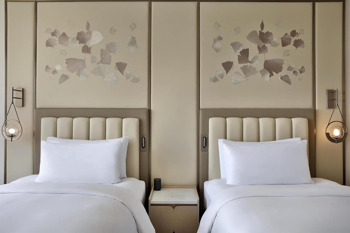 Ein Hotelzimmer mit zwei Betten, einem Nachttisch und Wandbildern.