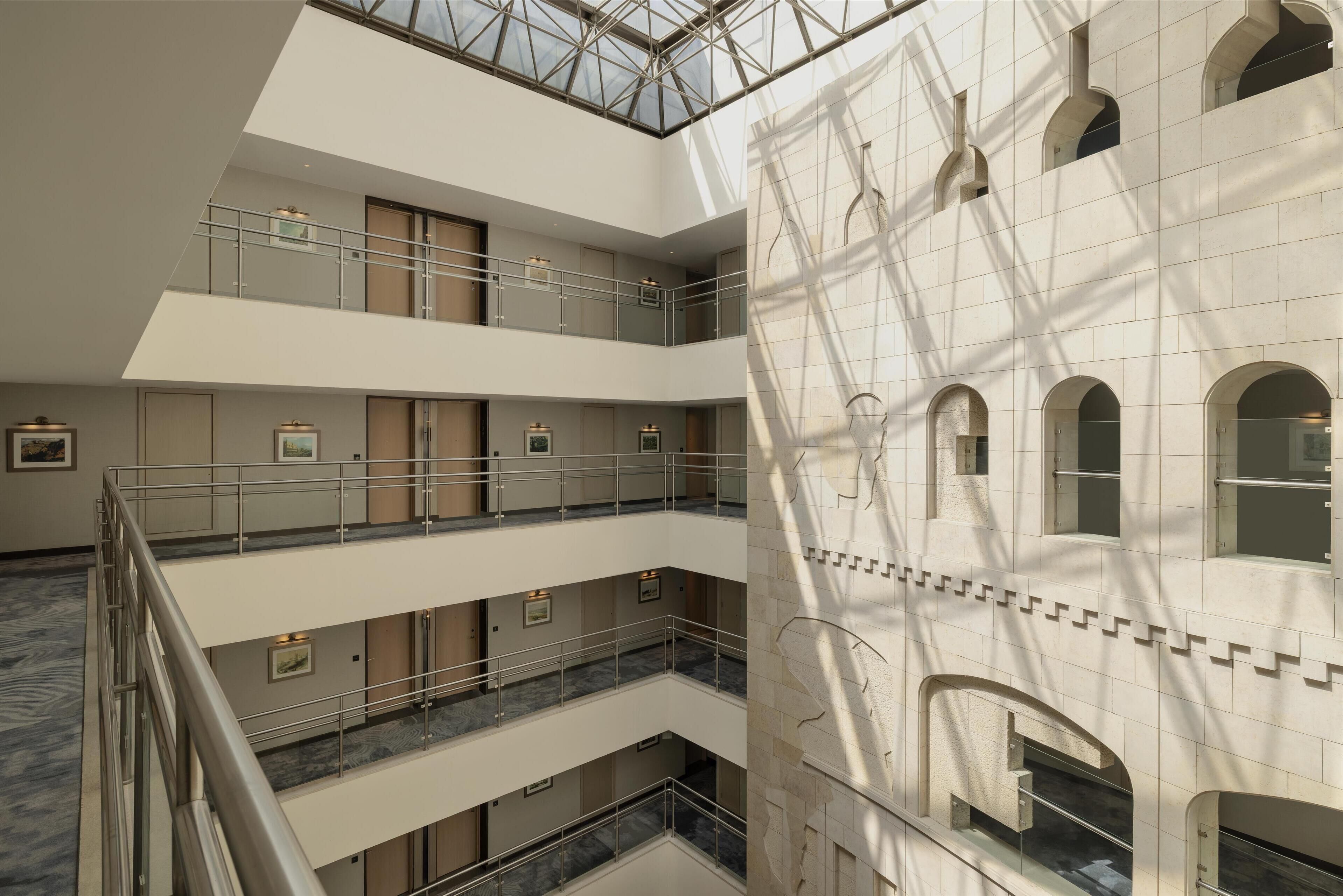 A multi-level interior with a central atrium, balconies, and a large arched window on the right.
