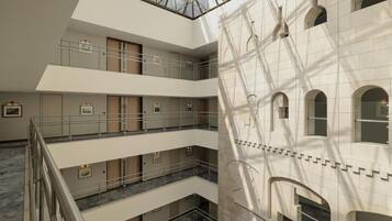 A multi-level interior with a central atrium, balconies, and a large arched window on the right.