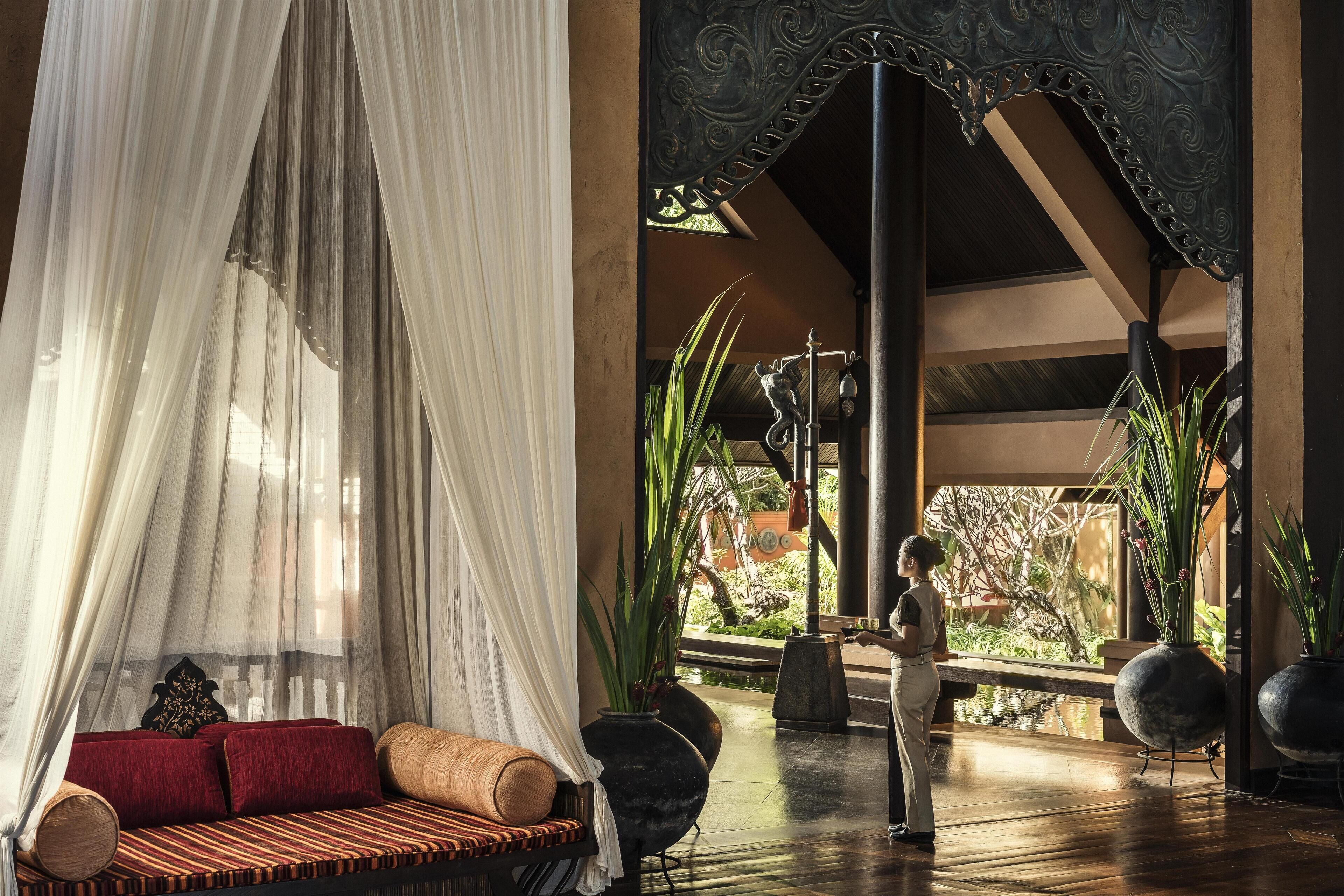 A room with a canopy bed, a wooden bench, and a view of a garden.