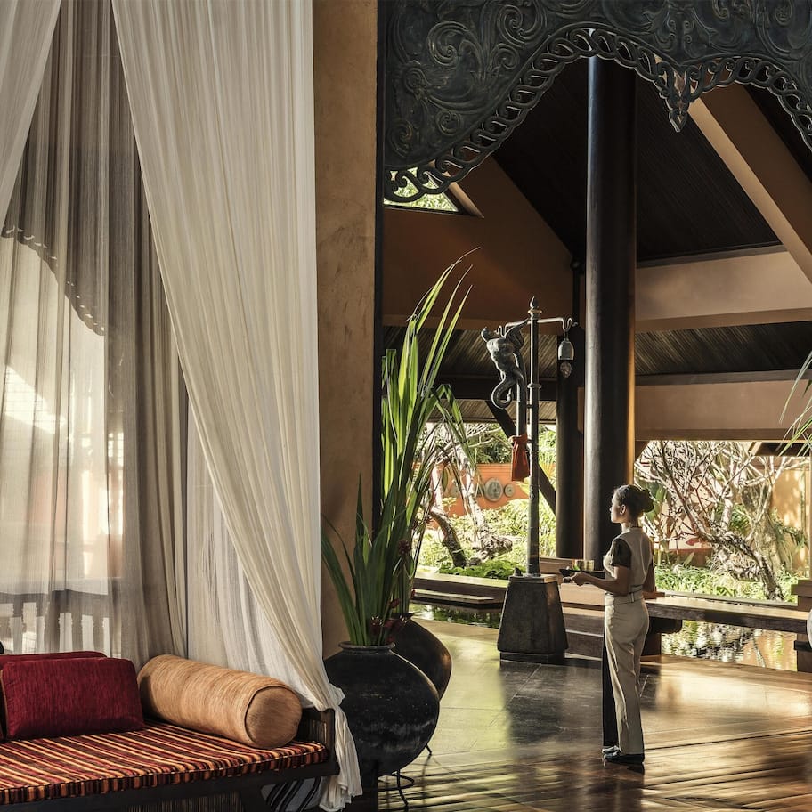 A room with a canopy bed, a wooden bench, and a view of a garden.
