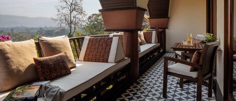 A balcony with a sofa, chairs, and a table with a drink.