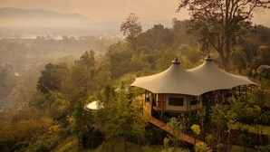 A treehouse with a white canopy roof, surrounded by lush greenery and a valley view. - Anantara Golden Triangle Elephant Camp & Resort (Chiang Saen)