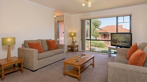 A living room with a sofa, coffee table, and TV. There are two lamps on side tables.