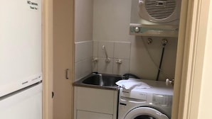 A compact kitchen with a washing machine, a sink, and a built-in microwave.