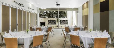 A conference room with round tables, chairs, and a projector screen.